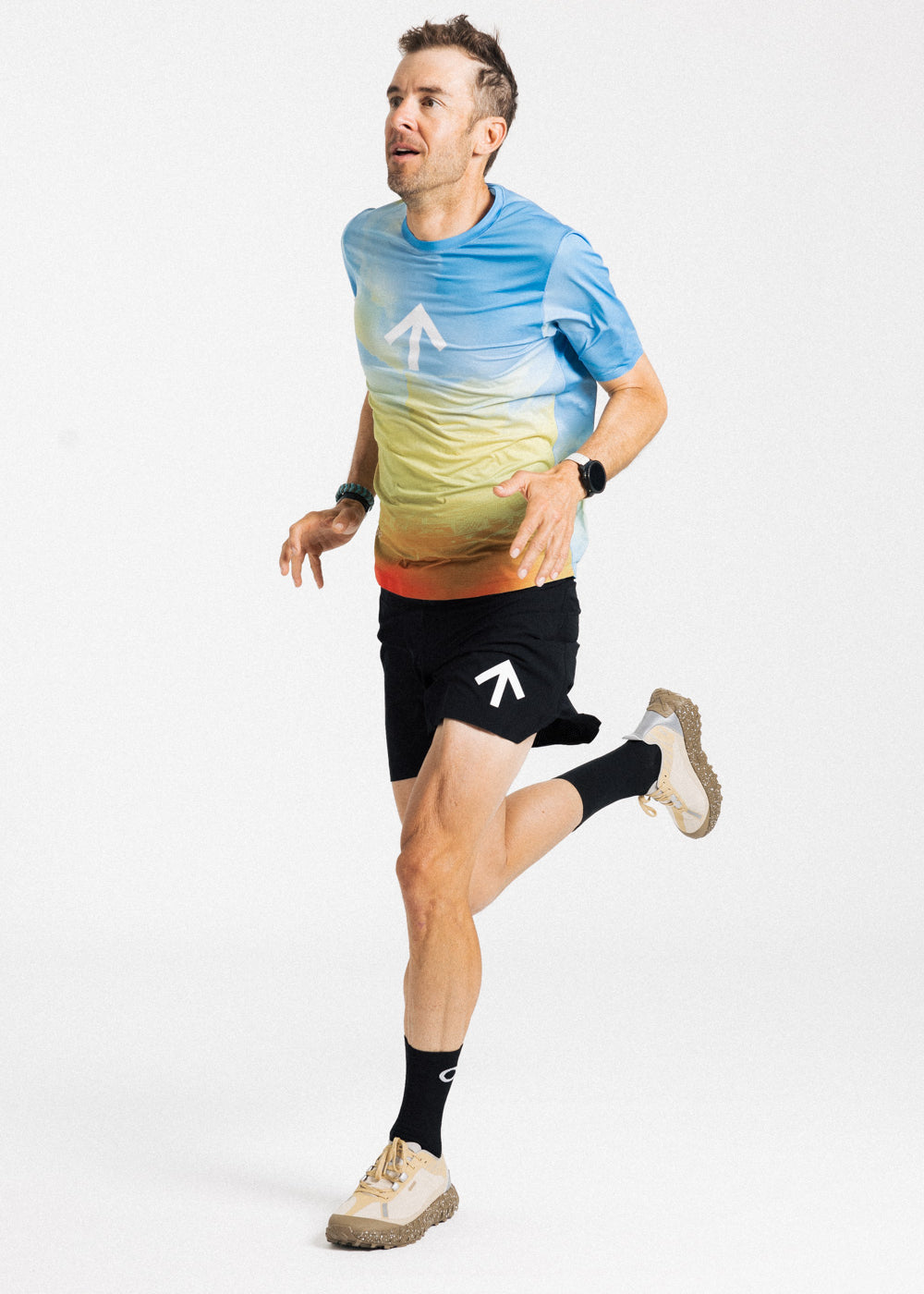 Male runner mid-stride in the AROW Marathon Short v.2 in Black and White with a blue and yellow gradient tee