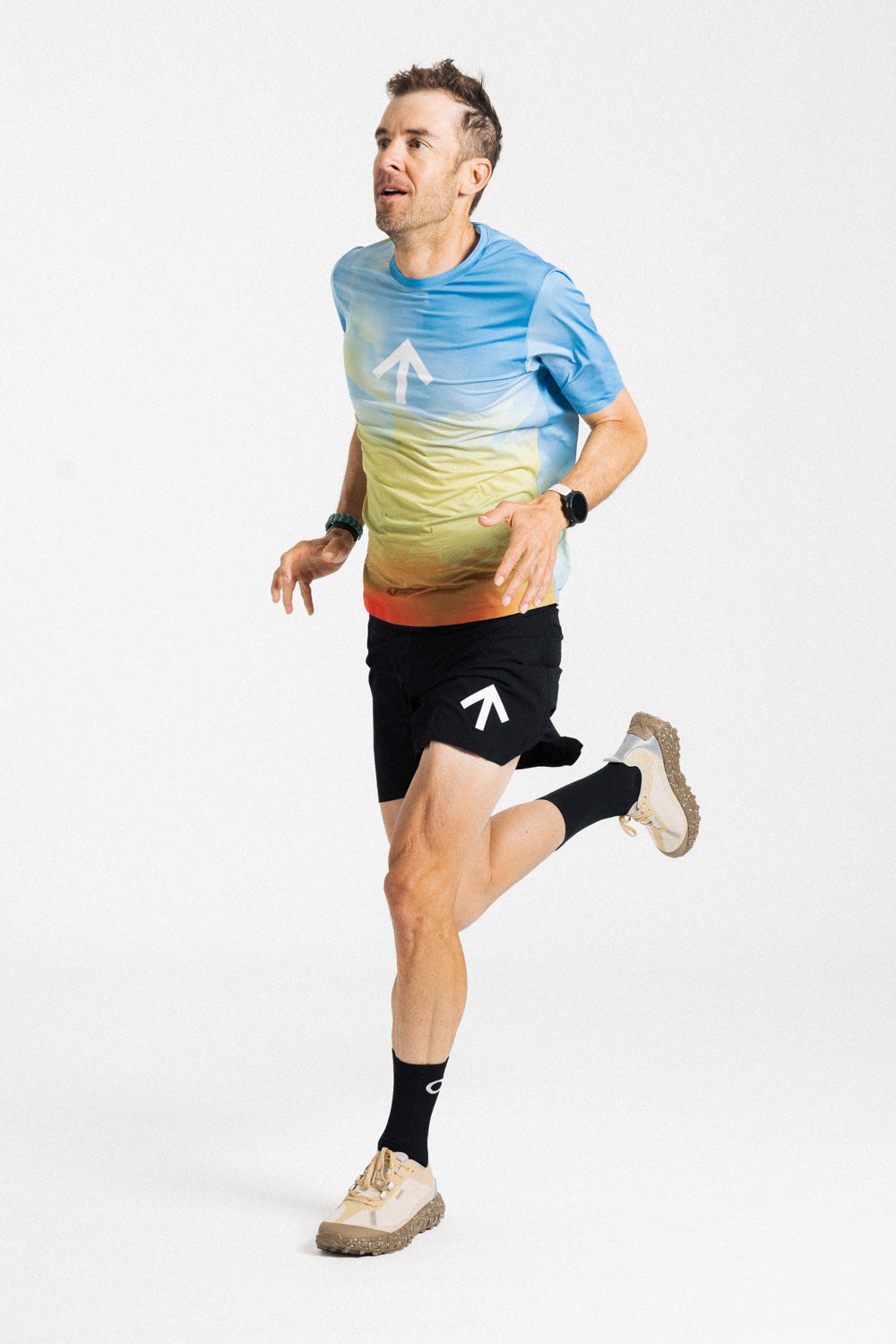 Male runner mid-stride in the AROW Marathon Short v.2 in Black and White with a blue and yellow gradient tee