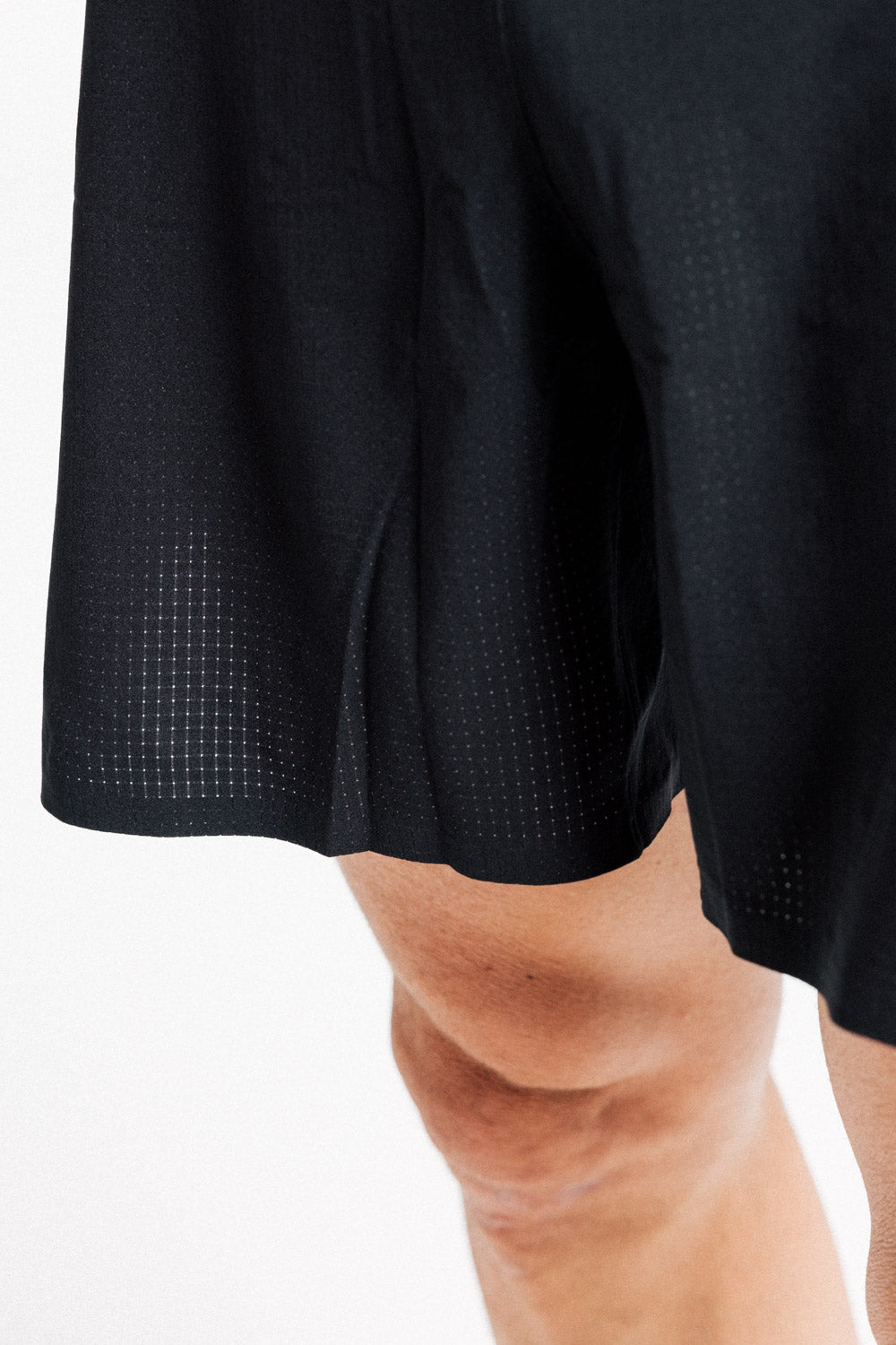 Close-up of the perforated fabric and split hem on the AROW Marathon Short v.2 in Black and White