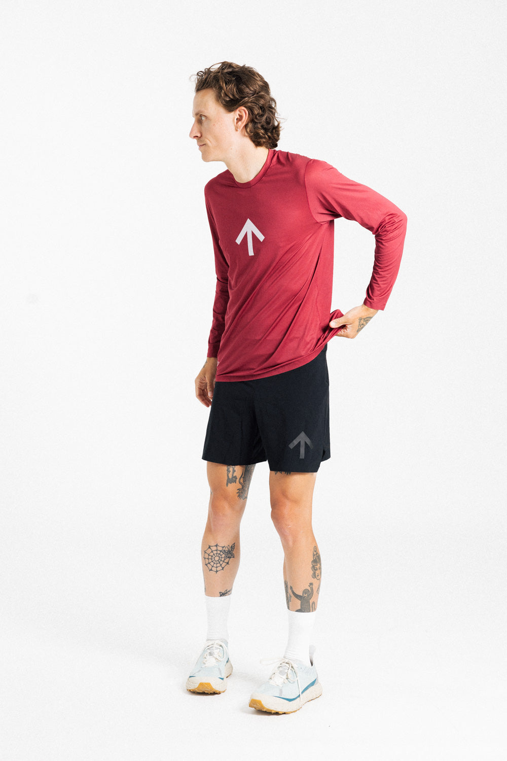 Male runner wearing the AROW Marathon Short v.2 in Black and Black with a red long sleeve top