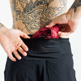 Close-up of a runner tucking a folded top into the rear waistband pocket of the AROW Marathon Short v.2 in Black and Black
