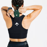Back view of a female runner storing a phone in the rear pocket of the AROW Women's Running Bra